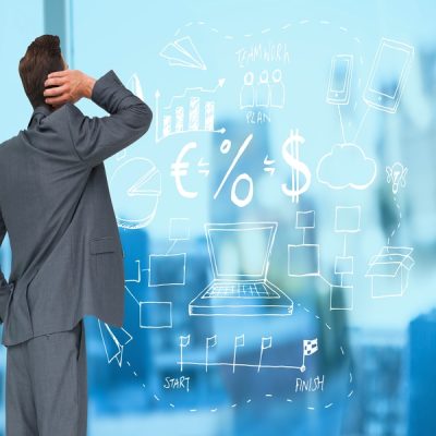 Digital composition of confused businessman looking at business related graphics on a glass wall